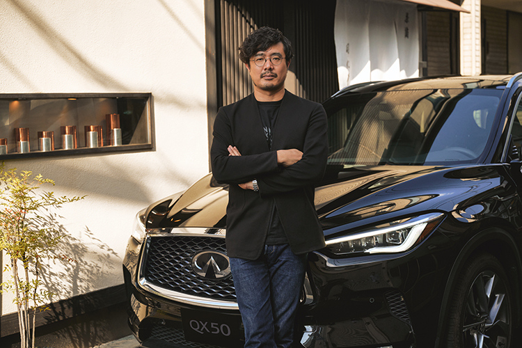 Takahiro standing in front of a INFINITI QX50 with arms crosssed.