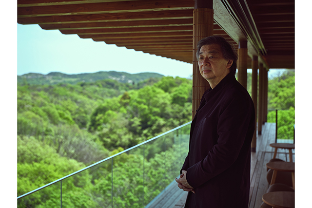 Architect Shigeru Ban standing on a wooden deck overlooking a forest