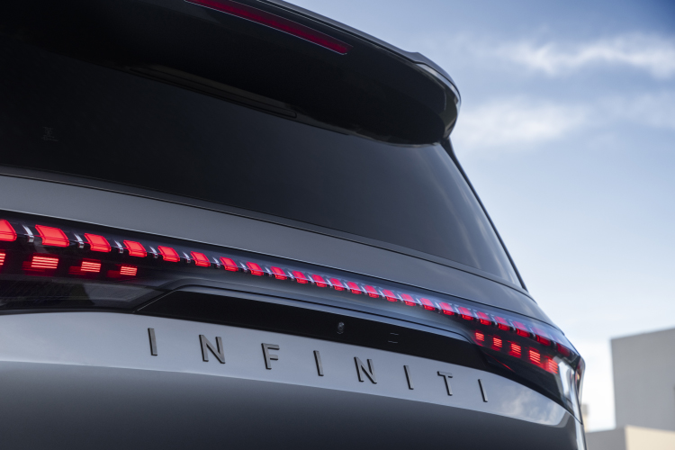 A close-up of the INFINITI nameplate decal under the taillights on a silver 2025 INFINITI QX80.