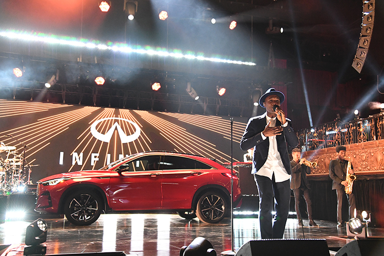Aloe Blacc performing on stage in front of a INFINITI QX55.