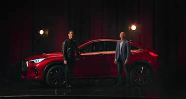 QX55 in a dark room with two people standing next to it.